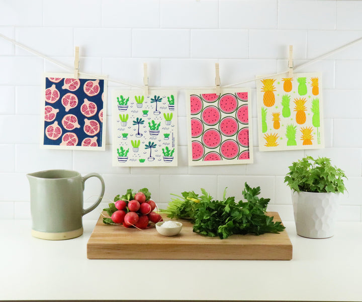 Bespoke Provisions Swedish dishcloths hanging from clothespins with pitcher, radishes and parsley in foreground.